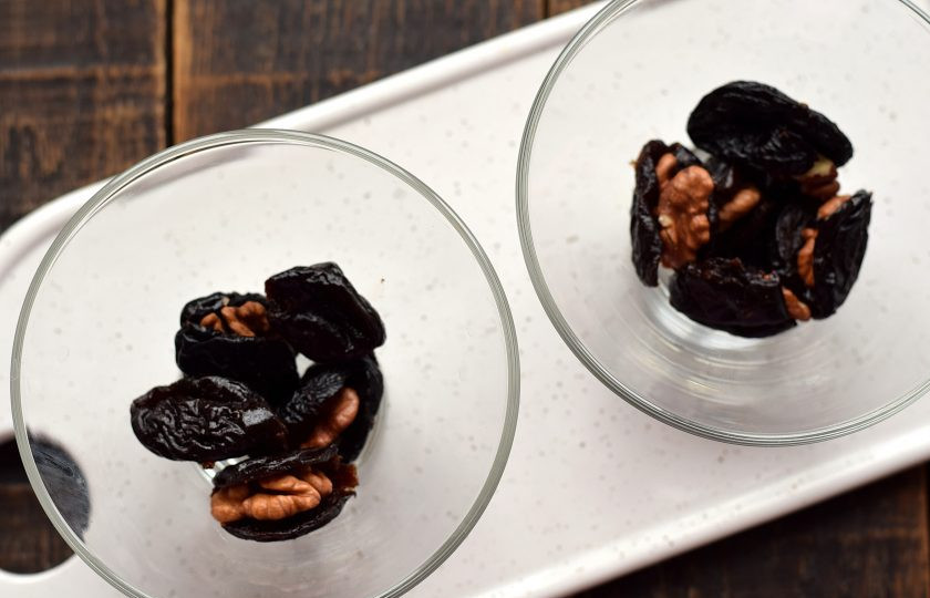 1. Этап. Чернослив с грецким орехом в сливках: Подготовьте две небольшие пиалочки. На дно каждой выложите по 5 заготовок из чернослива и орехов.