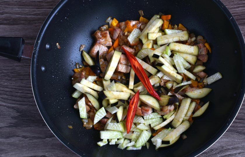 1. Этап. Пуктяй: Добавьте брусочки баклажана и кубики редьки. Положите острый перчик, разрезав его пополам и по желанию удалив семена, чтобы суп был менее острым. Перемешайте и прогрейте пару минут.