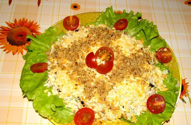 1. Этап. Салат Женский каприз: Листья салата вымыть, обсушить и выложить на плоское блюдо. По центру выкладываем заправленный салат, посыпаем его желтками и оставшимися грецкими орехами. Украшаем и подаем к столу.