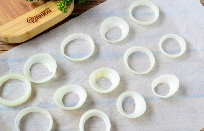 1. Этап. Хот-дог в луковых колечках: Репчатый лук очистите и порежьте на кружочки толщиной примерно 7-10 мм. Разберите кружочки на кольца. Нам понадобятся только самые большие кольца, их выложите на пергамент или большую деревянную досточку.