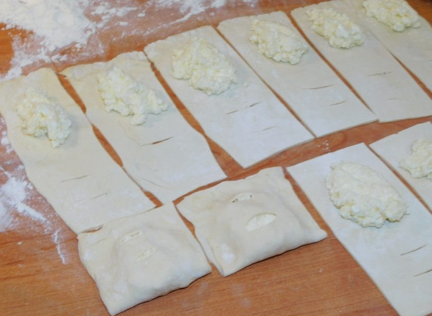 1. Этап. Творожные слойки: Выложите немного начинки на тесто и накройте половинкой с надрезами. Защипните края.