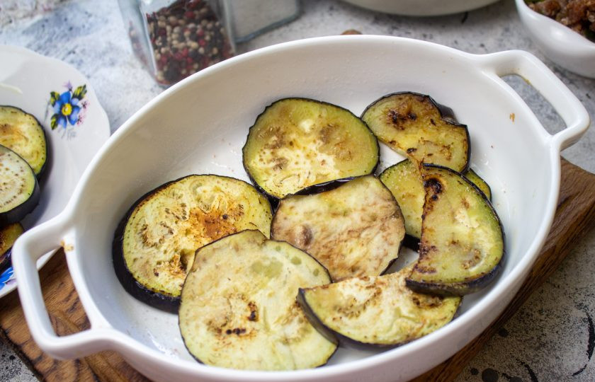 1. Этап. Запеканка из баклажанов по-гречески: Соберите запеканку. На дно формы выложите половину обжаренных баклажанов.