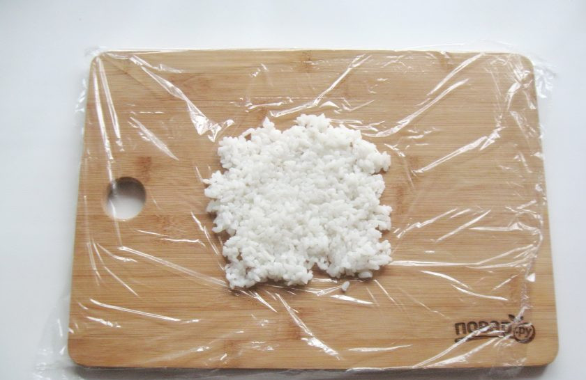 1. Этап. Рисовые шарики с рыбой: Порцию отварного риса выложите на пищевую пленку.