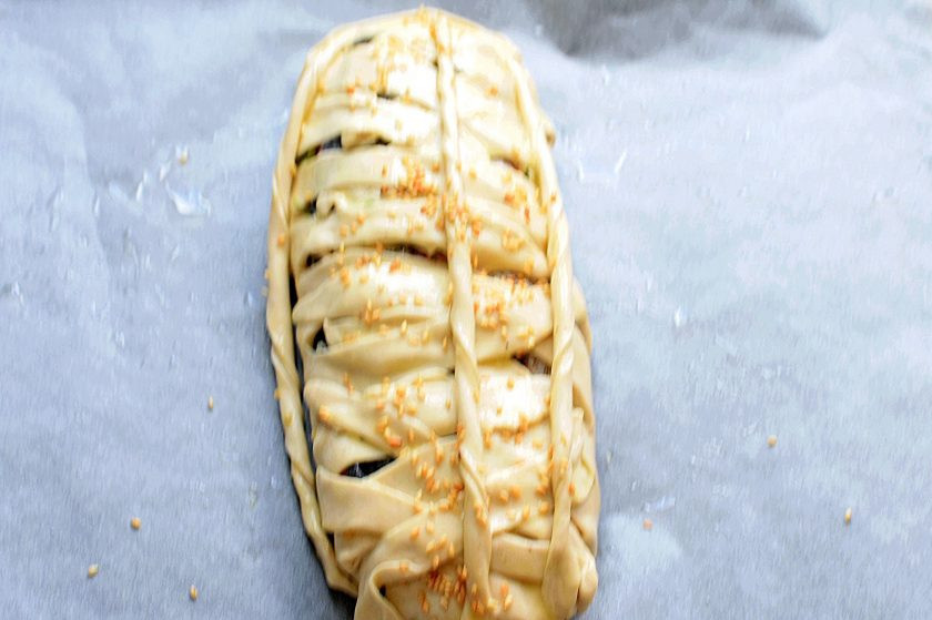 1. Этап. Пирог с форелью и капустой: Остатки теста раскатайте в жгутики и украсьте ими пирог. Смажьте подсоленным желтком. По желанию посыпьте кунжутом.