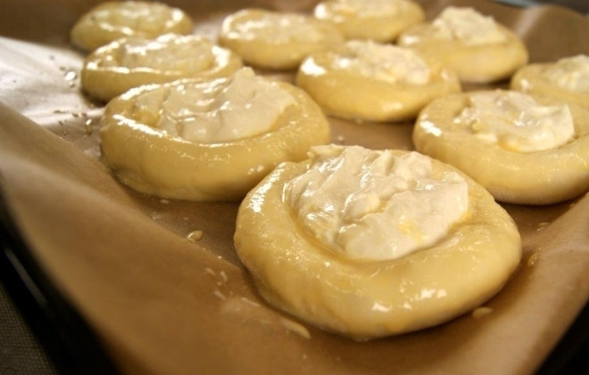 1. Этап. Шанежки с творогом: 9. Пергаментом застилаю противень, выкладываю сверху шанежки. В отдельной миске взбиваю яйцо, смазываю им каждую шанежку.