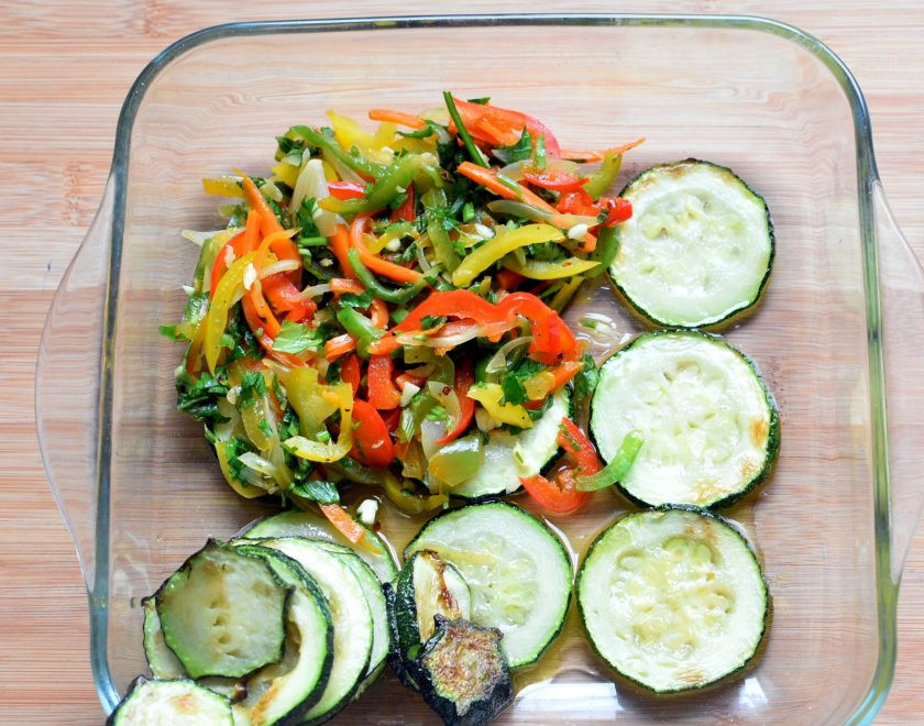 1. Этап. Острые пикантные цукини с овощами: Выложите в удобную посуду слой кружочков цукини. Сверху - слой овощей с зеленью.