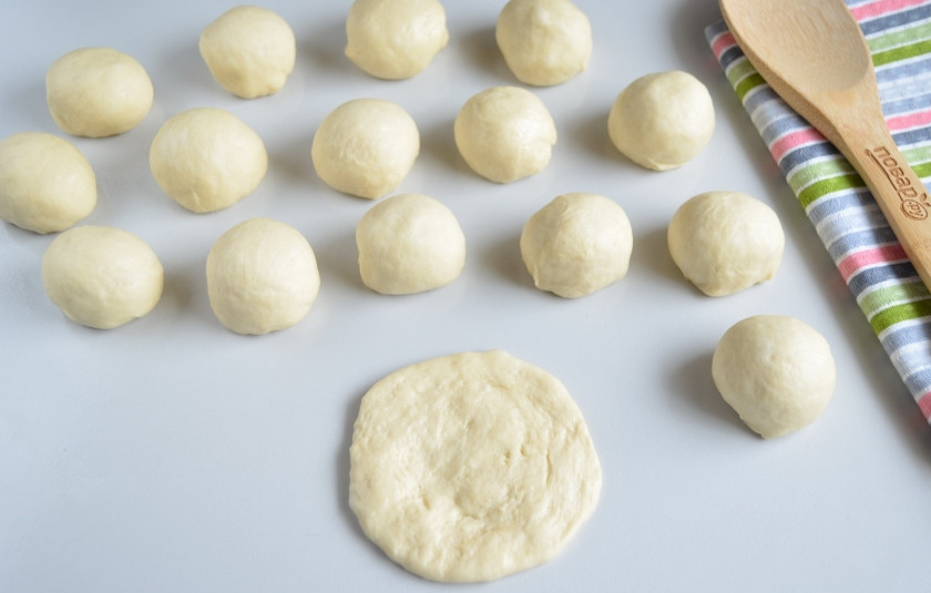 1. Этап. Беляши классические: Спустя час осадите тесто руками, разделите на небольшие шарики размером чуть больше грецкого ореха. Муку не нужно использовать, смажьте стол маслом, чтобы не тесто не прилипало. Приступаем к лепке. Шарик теста пальцами расплющите по столу.