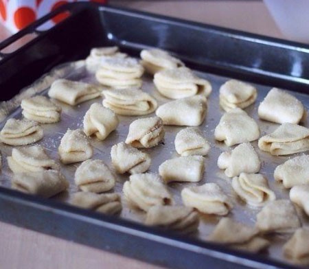 1. Stage. Curd Tea Cookies: Dip each circle in sugar on one side, then roll in half sugar inward and dip again in sugar on one side, fold the dough in half again and dip in sugar. Put the curd cookies on the parchment covered with parchment.