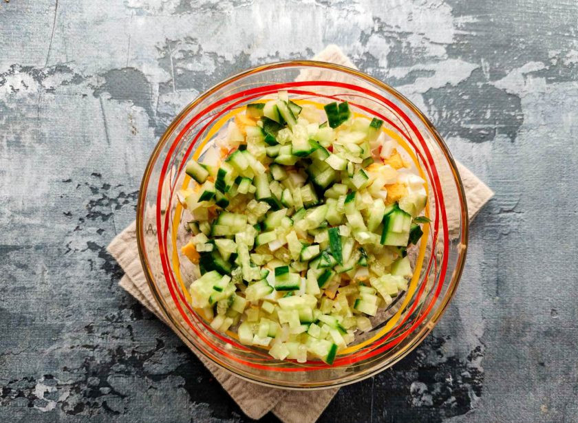 1. Этап. Крабовый салат с грецкими орехами: Огурец хорошо помойте под проточной водой, обсушите бумажным полотенцем, нарежьте кубиками и выложите в тарелку.