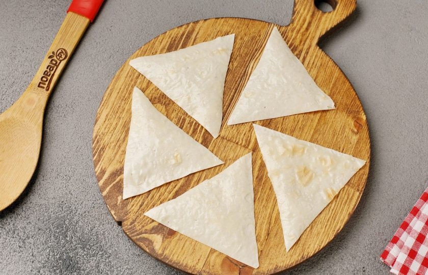 1. Этап. Чипсы из лаваша с яйцом, сыром и колбасой: Смажьте лаваш взбитым яйцом. Затем при помощи кухонных ножниц нарежьте полосками (в зависимости от желаемого размера чипсов). А затем каждую полоску разрежьте на квадратики или вот такие треугольники как у меня.