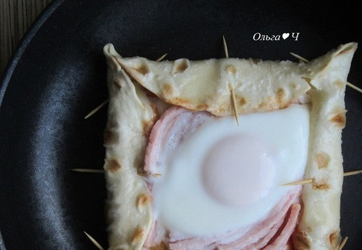 1. Этап. Яичница в лаваше Эти глаза напротив: Переложите заготовку на разогретую сухую антипригарную сковороду. Влейте немного кипятка и сразу накройте крышкой. Готовьте на огне выше среднего около 5 минут, чтобы яйцо на пару хорошо схватилось, а сыр в бортиках расплавился. Если любите жидкий желток, уменьшите время приготовления.