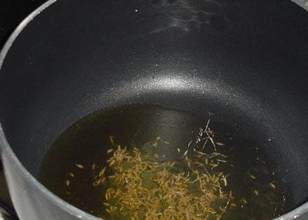 1. Этап. Вегетарианская черная фасоль Чили: Ставим кастрюлю на средний огонь. Наливаем примерно 3 столовые ложки оливкового масла и посыпаем 2 чайными ложками тмина. Когда семена тмина начнут шипеть и потрескивать переходим к следующему шагу.