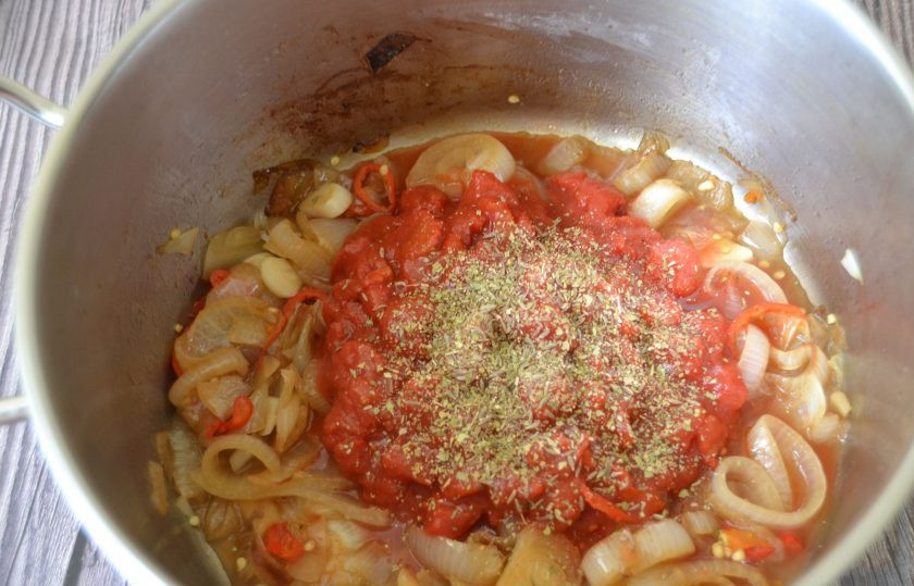 1. Этап. Куриный суп с тортильями: Добавьте в сотейник к луку помидоры в собственном соку, всыпьте по чайной ложке зиры и орегано.