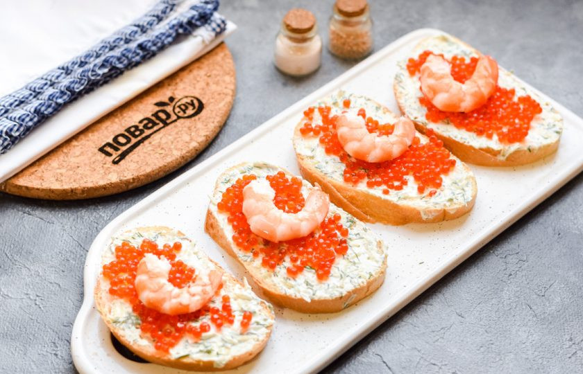 1. Этап. Бутерброды с красной икрой: Креветки очистите и выложите на каждый кусочек хлеба. Перед подачей на бутерброды можно добавить зелень по вкусу.