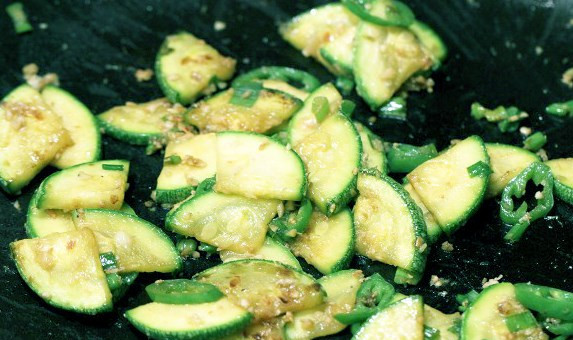 1. Этап. Кабачки по-корейски быстрые: Добавляем соус, лук, перец и чеснок. Обжариваем минуту или две.