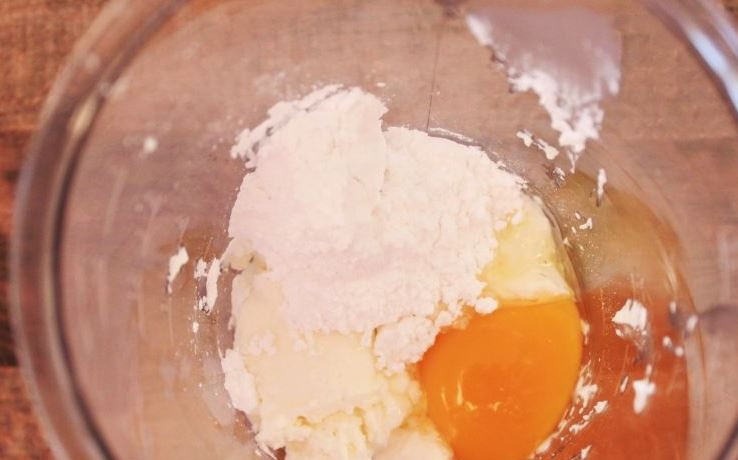 1. Этап. Простой чизкейк: Сливочный сыр поместите в чашу блендера. Вбейте к нему сырое куриное яйцо, всыпьте сахарную пудру и добавьте ром. Затем тщательно все взбейте до однородности.