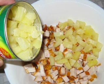 1. Этап. Салат с ананасом, курицей и сыром: Выкладываем курицу в удобную салатницу. Открываем консервированные ананасы, сливаем жидкость, она нам не понадобится. Добавляем готовые квадратики из ананасов в куриную нарезку.