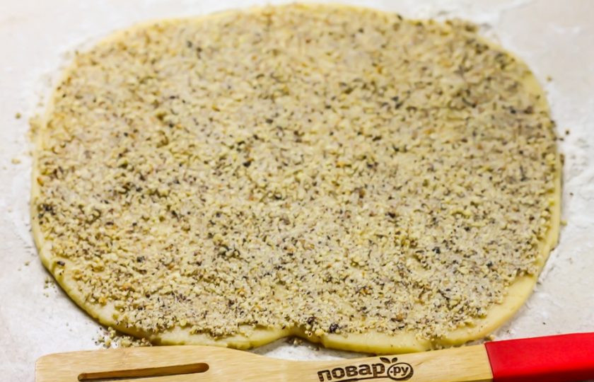 1. Этап. Печенье с грецкими орехами: Извлеките из холодильника песочное тесто, раскатайте его в не сильно тонкий пласт на рабочей поверхности. Присыпьте сверху ореховой крошкой и слегка пройдитесь по ней скалкой, но без сильного нажима, чтобы крошка впечаталась в тесто. Разогрейте духовку до 200 градусов.