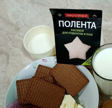 1. Этап. Шоколадный домик с рисовой полентой: Подготовим ингредиенты. В половину молока добавляем рисовую поленту, доводим до кипения и варим на медленном огне 8 минут. Снимаем с плиты, добавляем 50 гр сливочного масла и 50 гр сахара. Перемешиваем и оставляем остывать.