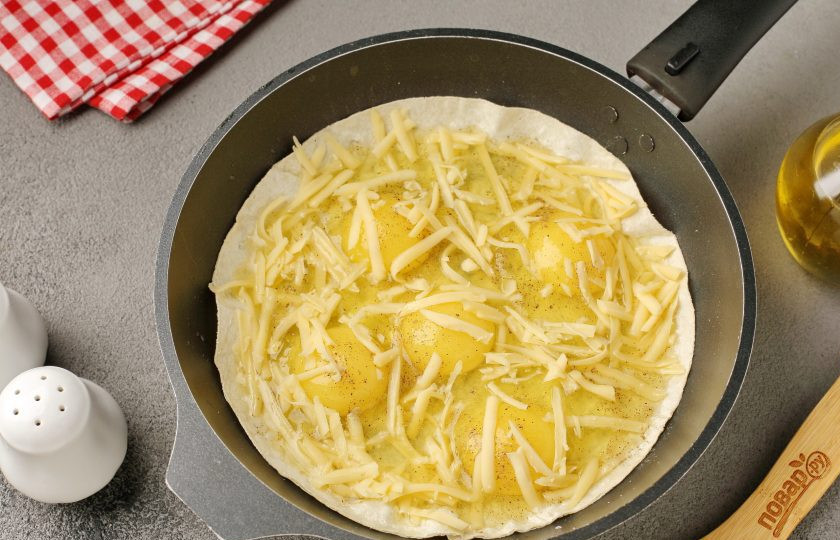 1. Этап. Яичница с помидором и сыром в лаваше на сковороде: Посыпьте яйца тёртым сыром.