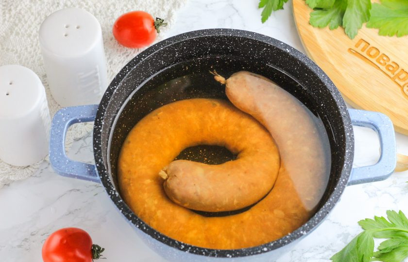 1. Этап. Домашняя варено-копченая колбаса: В казан или кастрюлю влейте жидкий дым и холодную воду. Поместите в жидкость колечко колбасы и отварите при 70-80 градусах 1-1,5 часа. Вода должна чуть подрагивать, но не кипеть! Если колбаса слишком надуется, то проколите ее в нескольких местах иголкой. После чего сразу же охладите в ледяной воде, чтобы прекратить процесс варки.