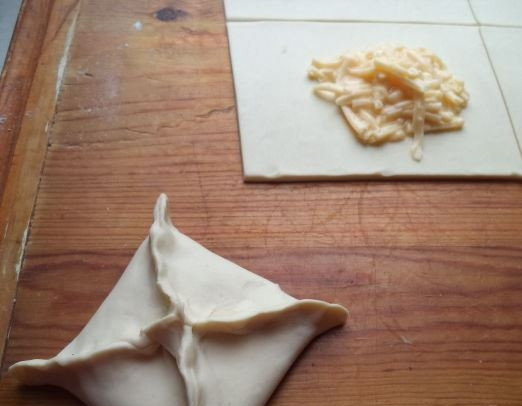 1. Этап. Хачапури с сулугуни в духовке: Соедините краешки теста так, как будто вы складываете конверт. Хорошенько их защипните, чтобы начинка не вытекла. Выложите получившиеся полуфабрикаты на противень. Смазывать его маслом не обязательно, так как слоеное тесто и так достаточно жирное и не будет прилипать. Духовку разогрейте до ста восьмидесяти градусов.