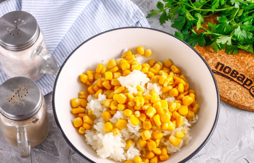 1. Этап. Салат с копченой курицей и рисом: Остуженный отварной рис выложите в глубокую емкость. Вскройте банку с консервированной кукурузой и слейте маринад, выложите ее в емкость.