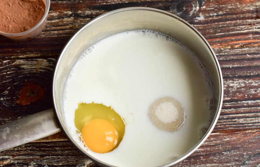 1. Этап. Профитроли с банановым кремом: В ковш влейте молоко, вбейте 1 куриное яйцо, всыпьте сахар.