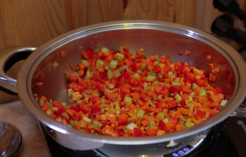 1. Этап. Рыбное филе, жаренное с овощами и креветками: Все остальные овощи вымойте и обсушите. Очистите перец от семечек, лук от шелухи, морковь от кожуры. Нарежьте все овощи кубиками. Влейте в сковороду оливковое масло и обжарьте на нем овощи до полуготовности с веточкой розмарина.