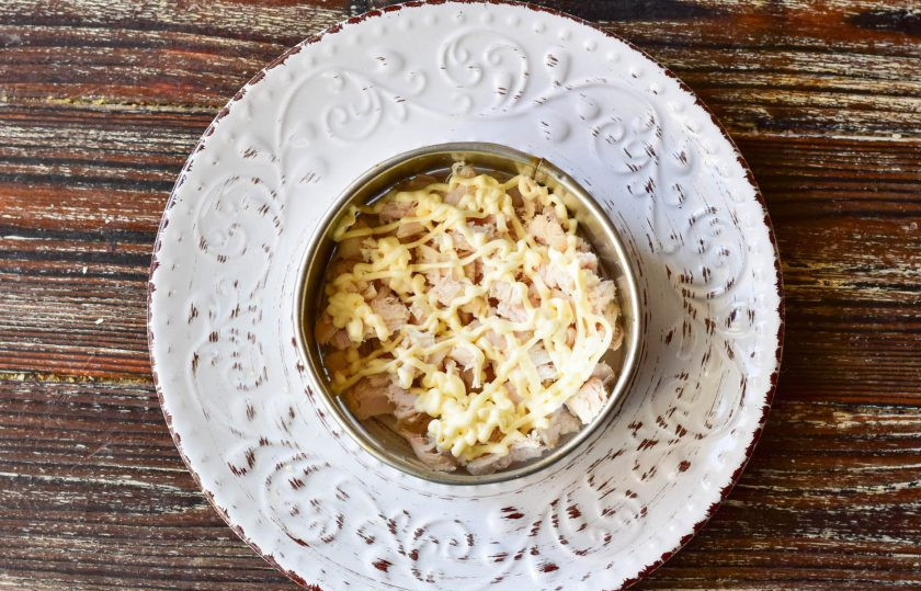 1. Этап. Оливье с ананасом: Первым слоем выложите мясо и сделайте сетку из майонеза.