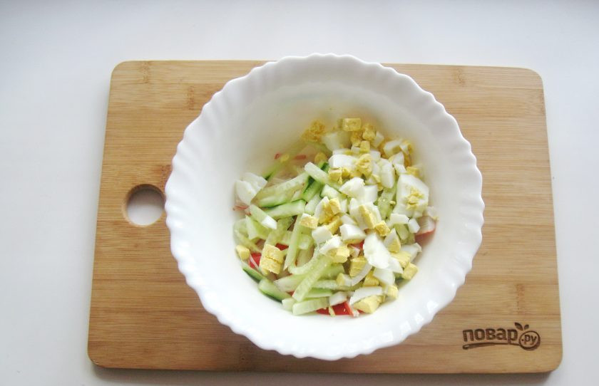 1. Этап. Салат с дайконом и крабовыми палочками: Яйца сварите вкрутую, очистите, нарежьте мелко и выложите в салатник.