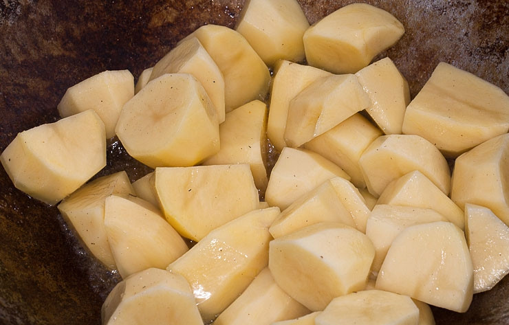 1. Этап. Баклажаны в казане на костре: Картофель почистите, промойте и крупной нарежьте. Отправьте его в казан на костре с маслом. Обжарьте до золотистого цвета, после чего уберите из казана.