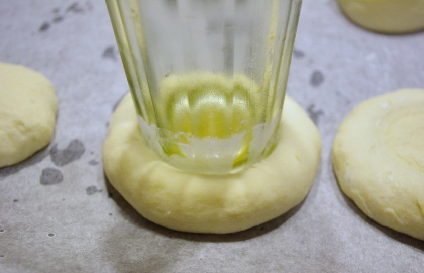 1. Этап. Ватрушки из дрожжевого теста: Дно стакана смочите в растительном масле, в каждой лепешке сделайте стаканом углубления.