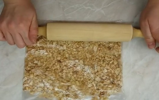 1. Этап. Бисквитный торт Подарочный: Очищенный арахис обжарьте на сухой сковороде до золотистого цвета, дайте остыть, затем переложите орехи в полиэтиленовый пакет и измельчите с помощью скалки.