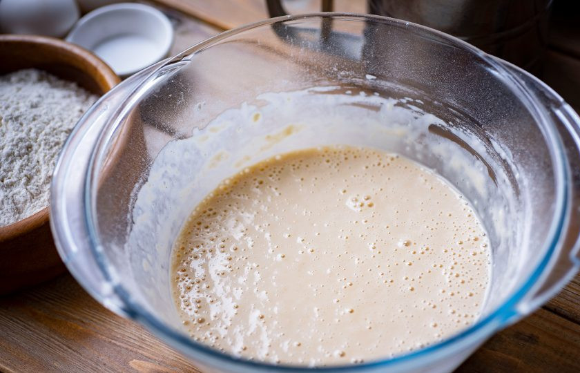 1. Этап. Тесто на топленом молоке: Венчиком перемешайте все ингредиенты до исчезновения мучных комочков — это опара. Накройте кухонным полотенцем миску с опарой и оставьте так на 30 минут.