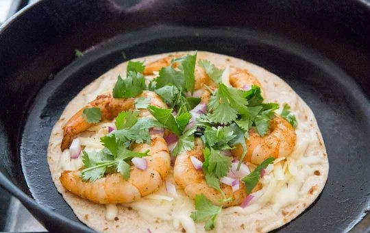 1. Этап. Закуска с креветками: 4. Оставьте последнюю лепешку на сковороде, посыпьте тертым сыром, выложите креветки, добавьте измельченный лук и зелень.