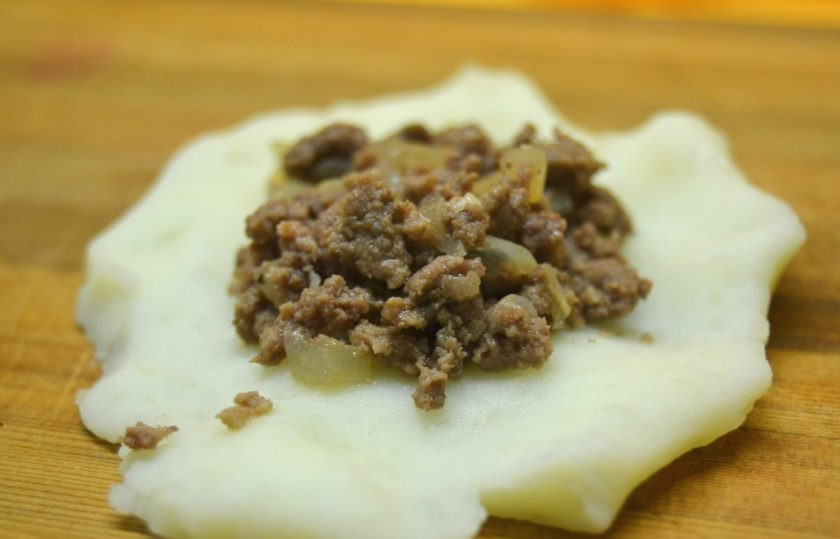1. Этап. Картофельные зразы с начинкой из фарша: 10. Возьмите небольшое количество картофеля, сформируйте из него лепешку. Выложите по центру небольшое количество начинки.