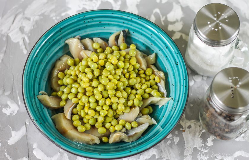 1. Этап. Салат из селедки с морковью: Вскройте банку с консервированным зеленым горошком, слейте маринад и выложите необходимую часть горошка в емкость.