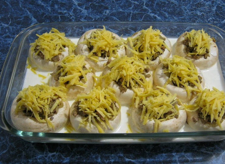 1. Этап. Грибы, фаршированные фаршем: Вливаем сметану в форму так, чтобы она только на половину прикрывала грибные шляпки. Затем на каждый грибочек кладем небольшое количество сыра. Ставим форму в разогретую до 180 градусов духовку и готовим в течение 30-35 минут. Затем выкладываем наши фаршированные грибы на тарелку, украшаем и подаем гостям. Приятного аппетита!