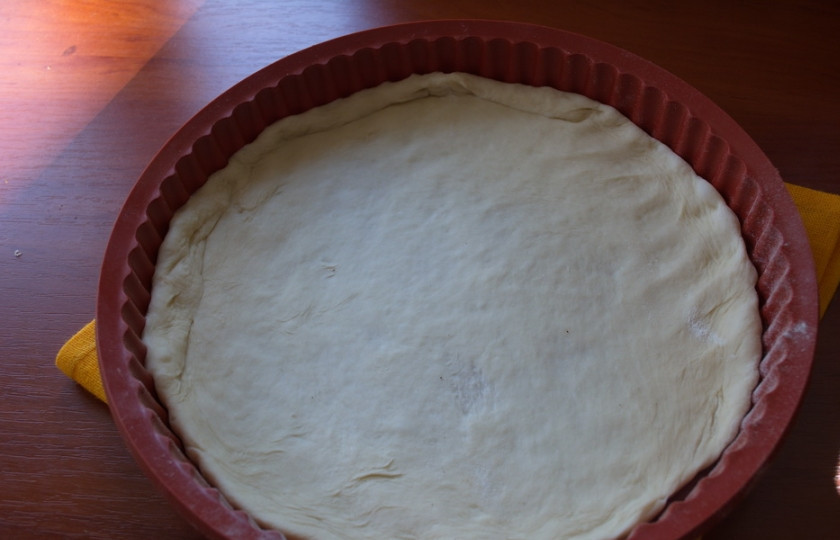 1. Этап. Пицца с сосисками: Тесто разделите на 2 части. Выложите в форму для запекания. Предварительно раскатайте его на столе в пласт. Так удобнее будет выкладывать. Я предпочитаю тонкий корж пиццы. Поэтому раскатываю тонко.