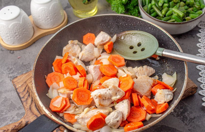 1. Этап. Лобио из фасоли с курицей: Морковь нарежьте тонкими кружочками и отправьте в сковороду, жарьте до мягкости овощей.