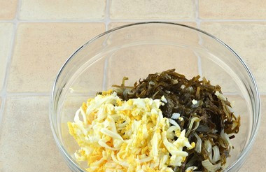 1. Этап. Морская капуста с яйцом: Смешиваем в посуде яйца вместе с обжаренной капустой и луком. Добавляем мелко порубленный чеснок. Перемешиваем хорошенько, пока масса не станет однородной.