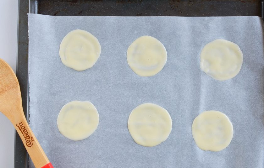 1. Этап. Печенье с пожеланиями: Застелите два противня силиконовыми ковриками, можно использовать специальный пергамент пропитанный силиконом, он белого цвета, отлично справляется с выпечкой, не прилипает, обычный пергамент не подойдет. Набирайте тесто по половине столовой ложки примерно, можно по целой. Тыльной стороной распределяйте тонким слоем, образовывая круг.