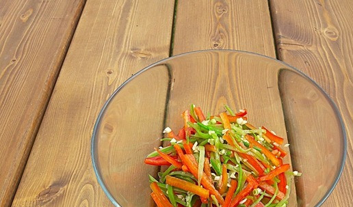 1. Этап. Китайский салат с молодым зеленым горошком: Сложить в емкость горкой горошек, перец, чеснок, соль, сахар. Нагреть масло и вылить на специи. Так смешаются все вкусы салата. Перемешать.