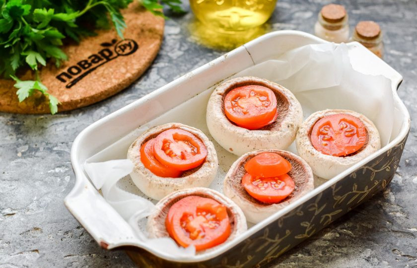 1. Этап. Шампиньоны с моцареллой в духовке: Черри нарежьте небольшими пластинами, выложите в грибы. Соль и перец добавьте по вкусу.