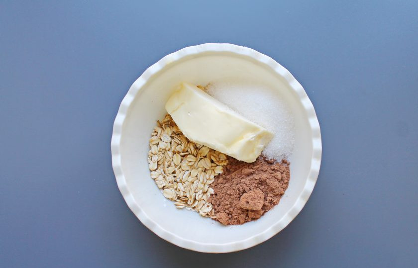 1. Этап. Овсяные шарики: В миску насыпьте овсяные хлопья, выложите сливочное масло, всыпьте сахар и какао порошок.