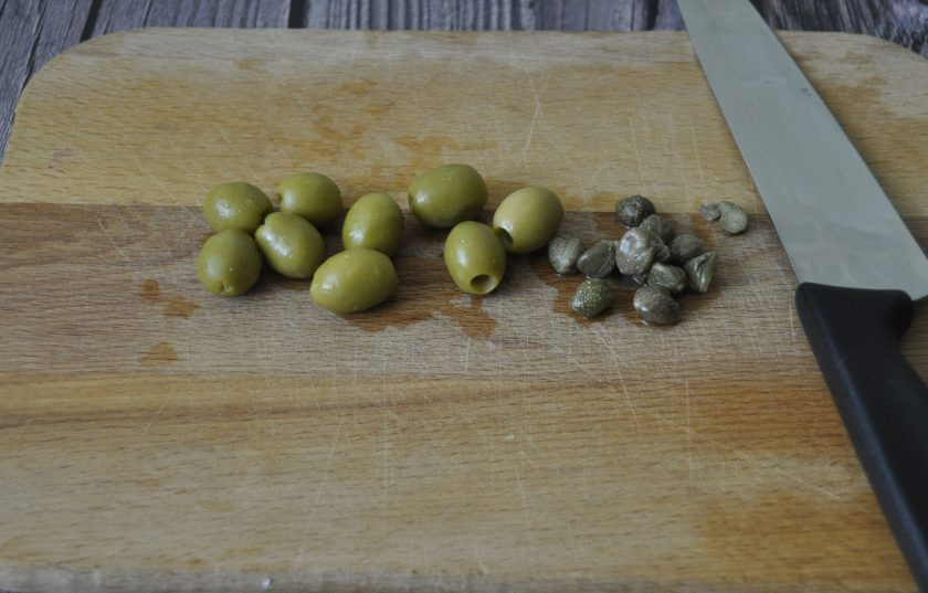 1. Этап. Пенне с лососем: Выложите на разделочную доску зеленые оливки и каперсы.
