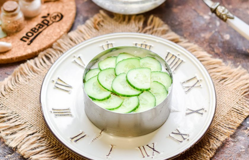 1. Этап. Слоеный салат с семгой и рисом: Свежий огурец нарежьте тонкими пластинами, выложите следующим слоем в салат.