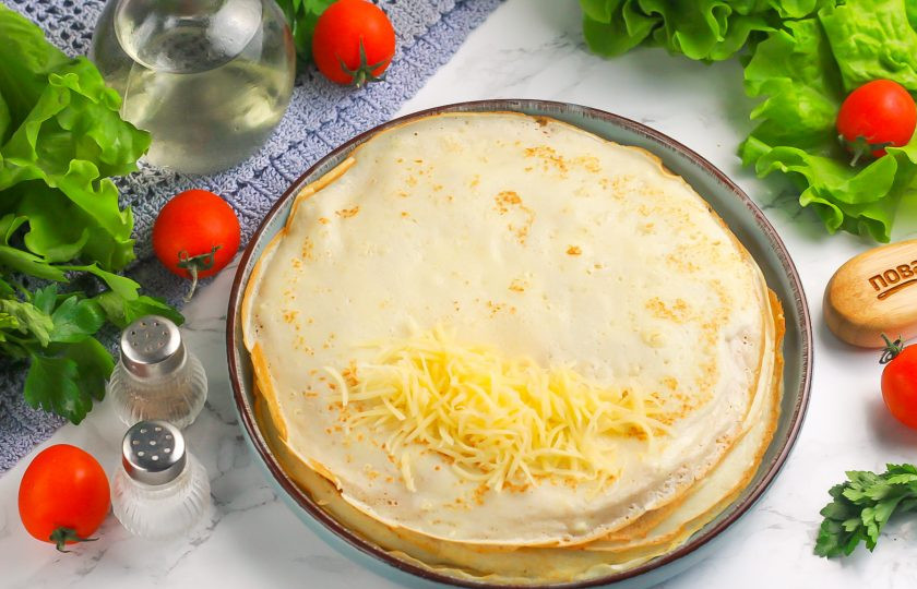 1. Этап. Блинчики с сыром и беконом: Выложите на край теплого блина 1 ст.л. натертого сыра и сверните в виде рулетика, завернув края внутрь.