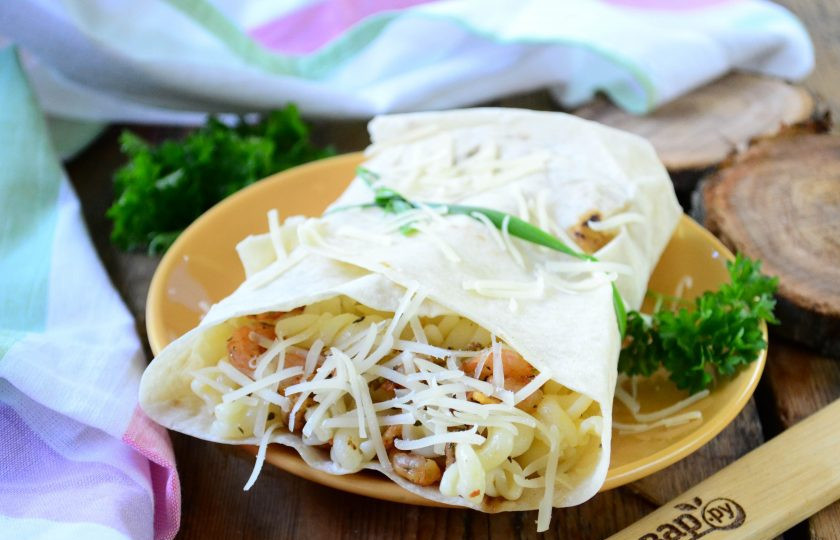 1. Этап. Паста с креветками в лаваше: Круглый лист лаваша разрежьте пополам. На каждую половину положите макароны с креветками, заверните лаваш в виде конверта и закрепите зеленым луком. Сверху присыпьте натертым на мелкой терке твердым сыром.